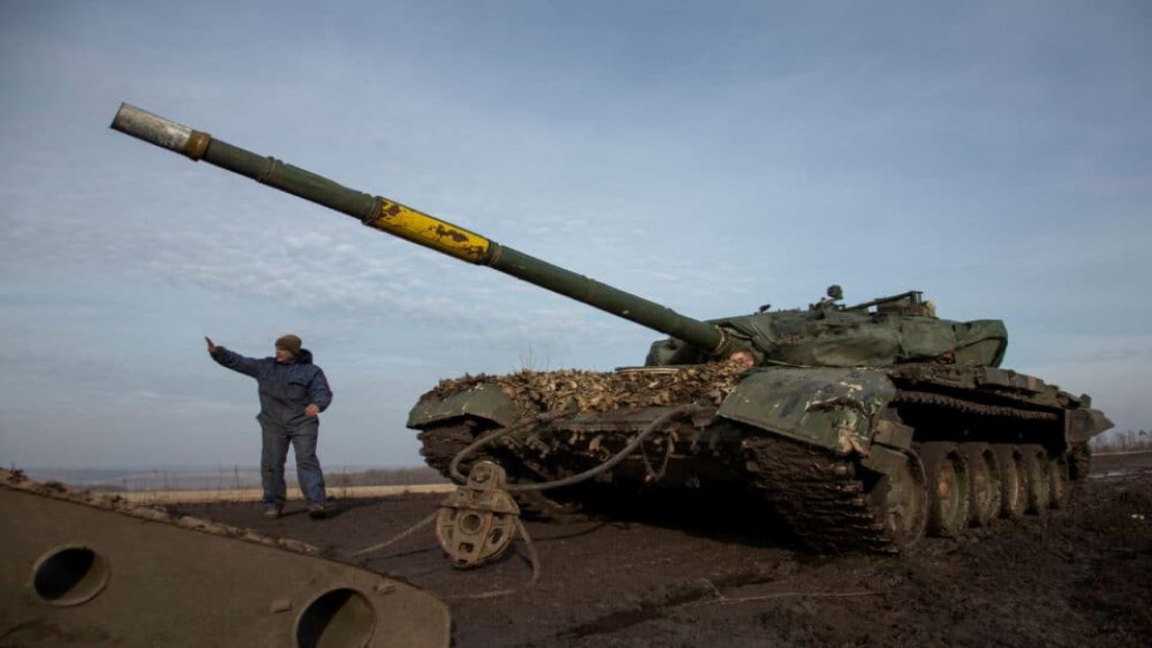 Seorang prajurit Ukraina memberi isyarat sambil menarik tank yang rusak ke sebuah truk di dekat kota garis depan Bakhmut. (Istimewa/Cyprus-Mail)