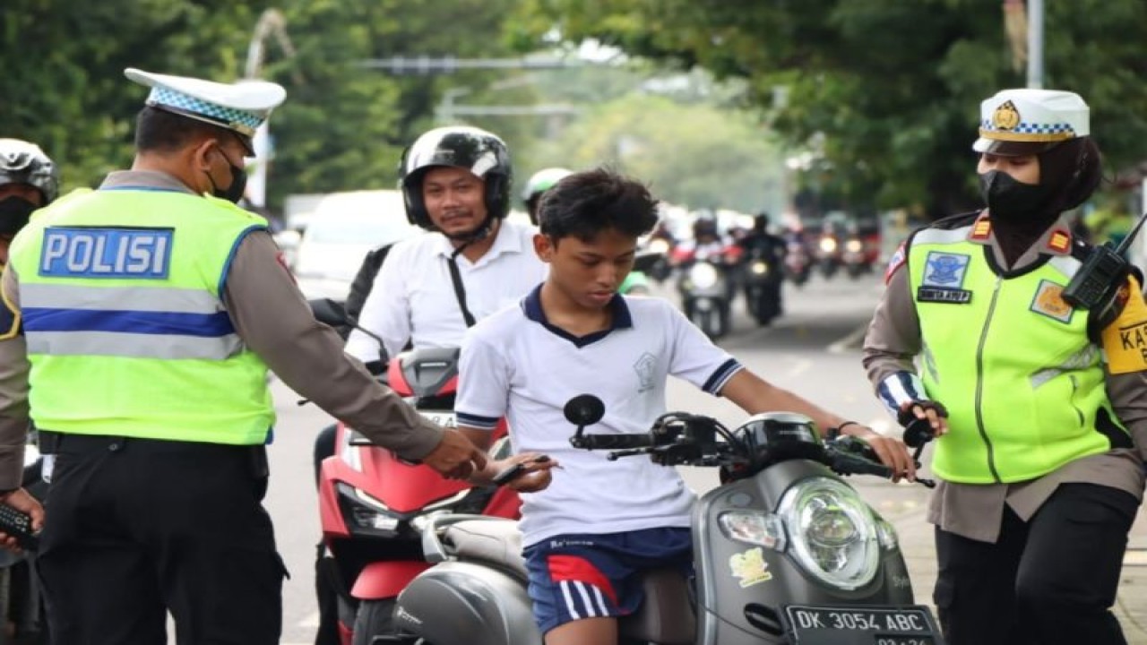 Anggota Satuan Lalu Lintas Kepolisan Resor Kota Denpasar sedang menindak seorang anak pengemudi motor yang tidak menggunakan helm pada hari pertama pelaksanaan Operasi Keselamatan Agung 2023 di salah satu ruas jalan di Kota Denpasar, Bali, Selasa (7/2/2023). ANTARA/HO-Humas Polresta Denpasar.
