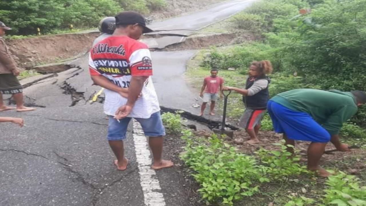 Warga mengamati bagian jalan yang rusak akibat tanah longsor di jalan Sabuk Merah yang menghubungkan Sadi dengan Baukama di Kabupaten Belu, Provinsi NTT. (ANTARA/HO BPBD Provinsi NTT)