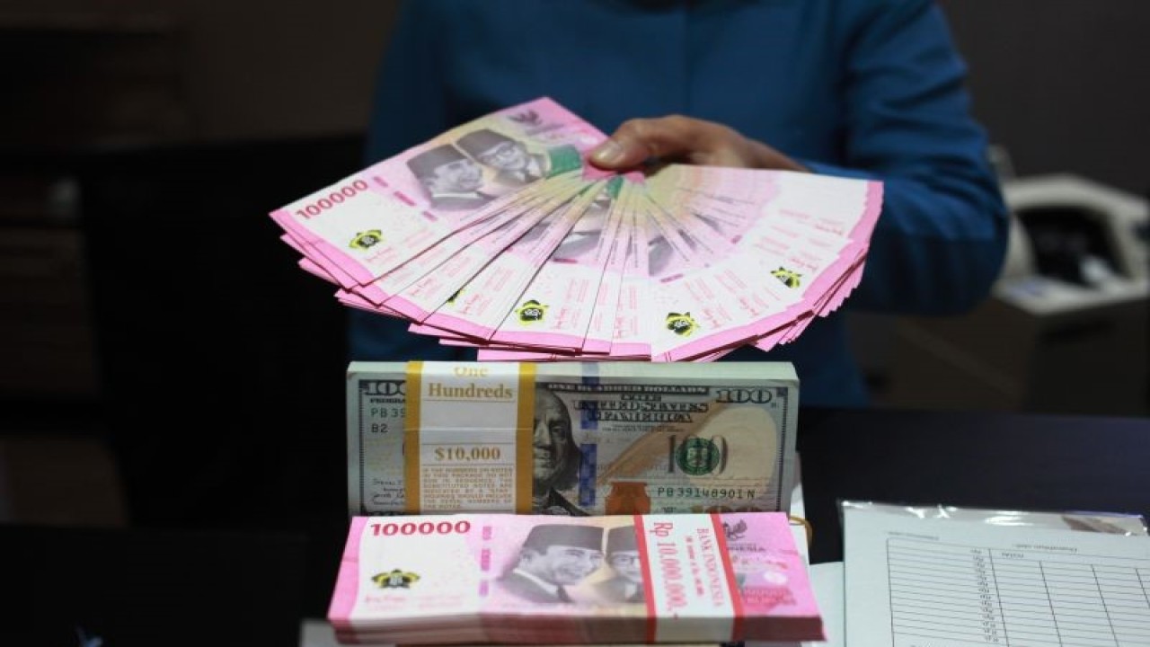 Petugas menunjukkan uang dolar AS dan uang rupiah di salah satu kantor cabang PT. Bank Mandiri Persero Tbk, Jakarta, Selasa (31/1/2023). ANTARA FOTO/Reno Esnir/tom