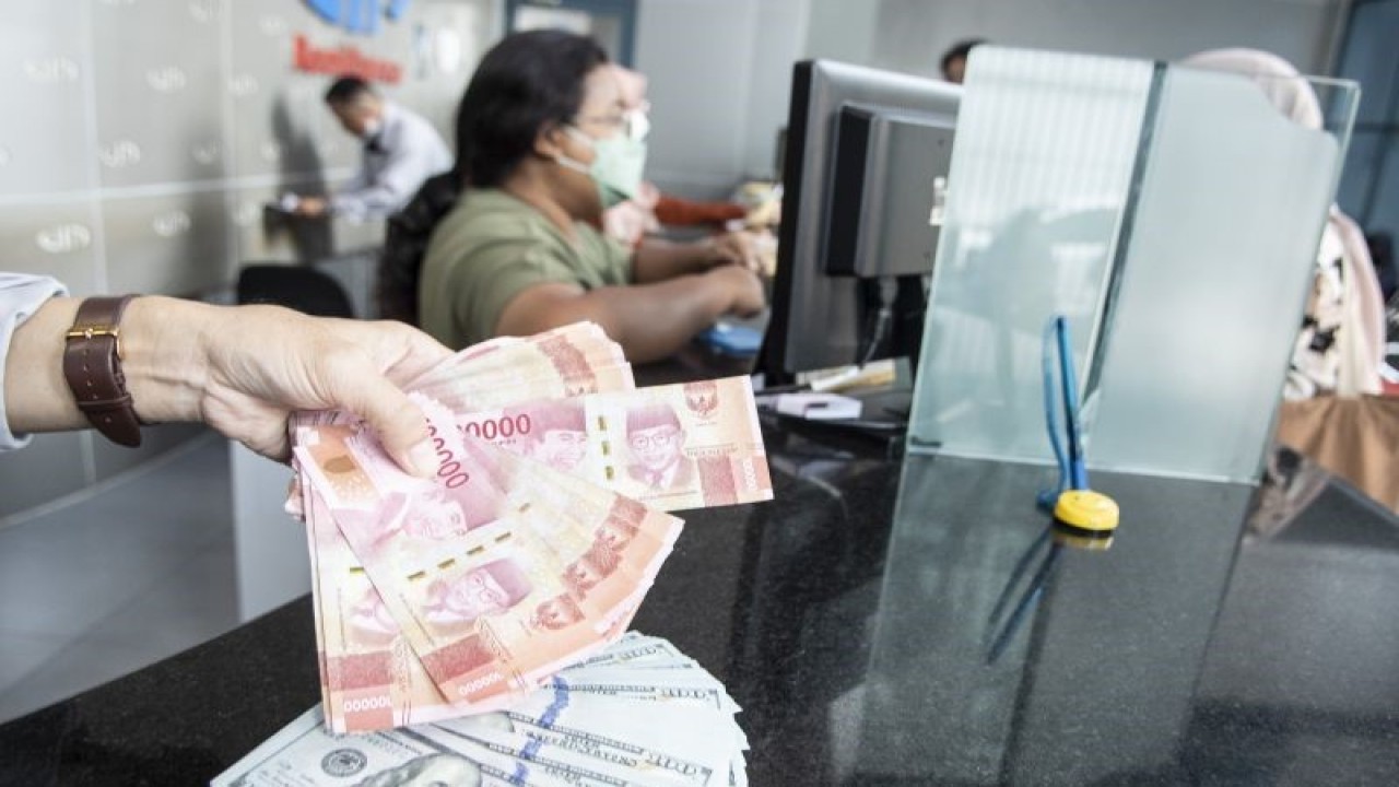 Petugas menunjukkan uang pecahan rupiah dan dolar AS di gerai penukaran mata uang asing VIP (Valuta Inti Prima) Money Changer, Jakarta, Selasa (3/1/2023). ANTARA FOTO/Muhammad Adimaja/foc.