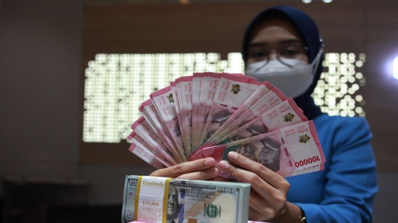 Petugas menunjukkan uang dolar AS dan uang rupiah di salah satu kantor cabang PT. Bank Mandiri Persero Tbk, Jakarta, Selasa (31/1/2023). ANTARA FOTO/Reno Esnir/tom.