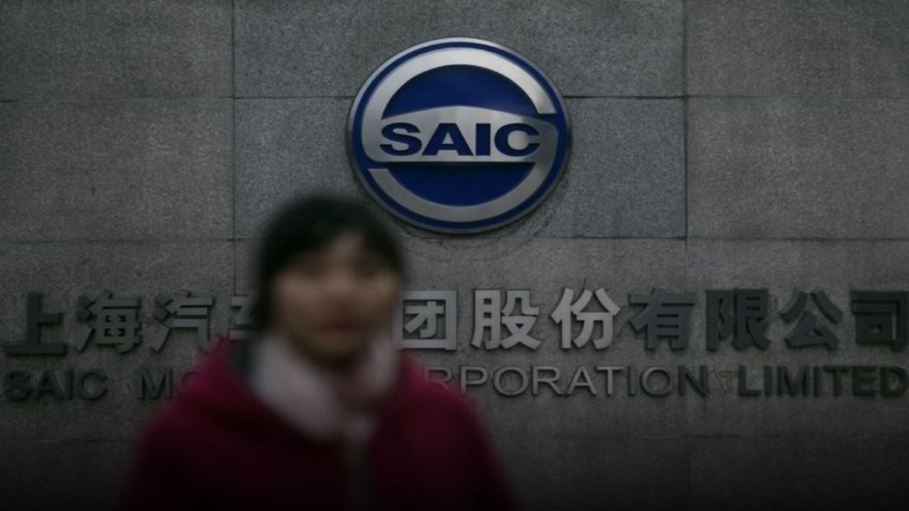 Seorang wanita berjalan melewati gerbang Saic Motor Corporation Limited di Shanghai, China, 26 Januari 2013. (Reuters)