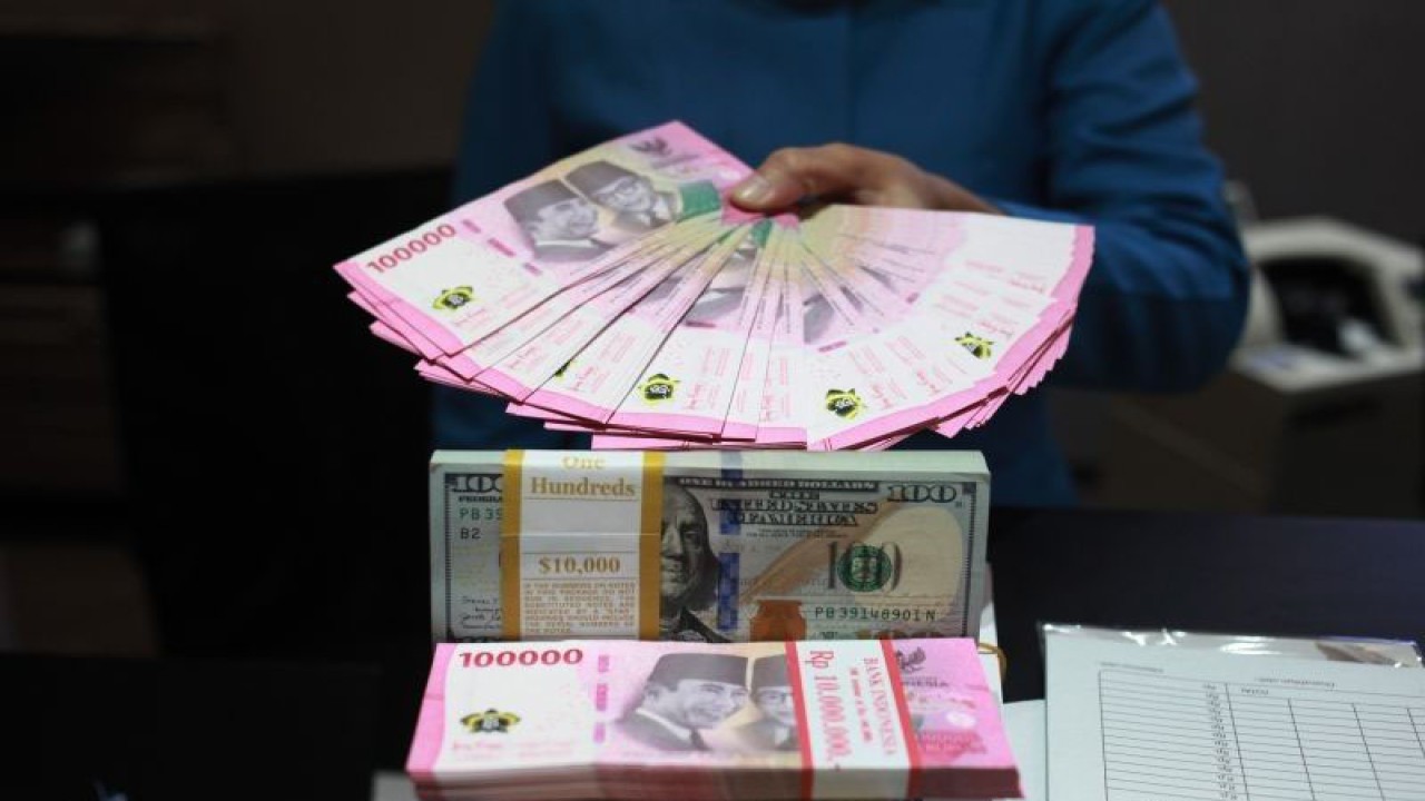 Petugas menunjukkan uang dolar AS dan uang rupiah di salah satu kantor cabang PT. Bank Mandiri Persero Tbk, Jakarta, Selasa (31/1/2023). (ANTARA FOTO/Reno Esnir/tom)