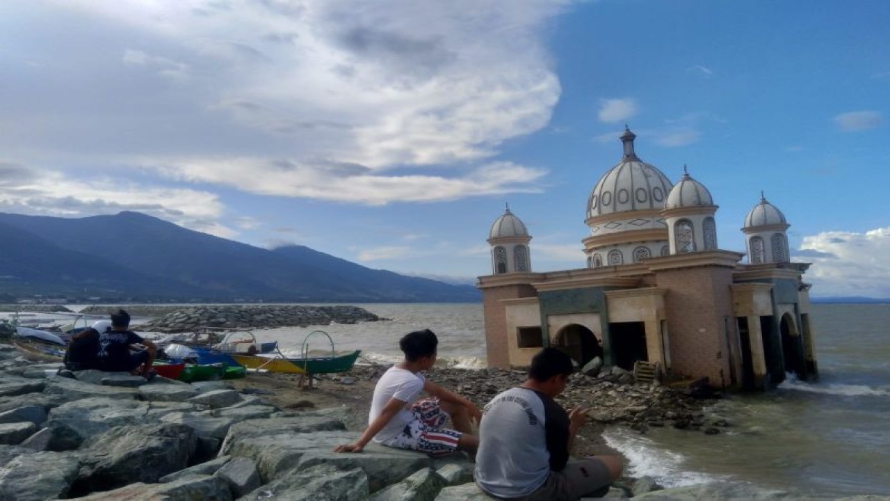 Sejumlah warga menunggu datangnya waktu berbuka puasa atau ngabuburit di sekitar masjid terapung yang rusak akibat bencana gempa dan tsunami, di Kota Palu, Sulawesi Tengah, (24/3). (Foto ANTARA/Nur Amalia Amir)