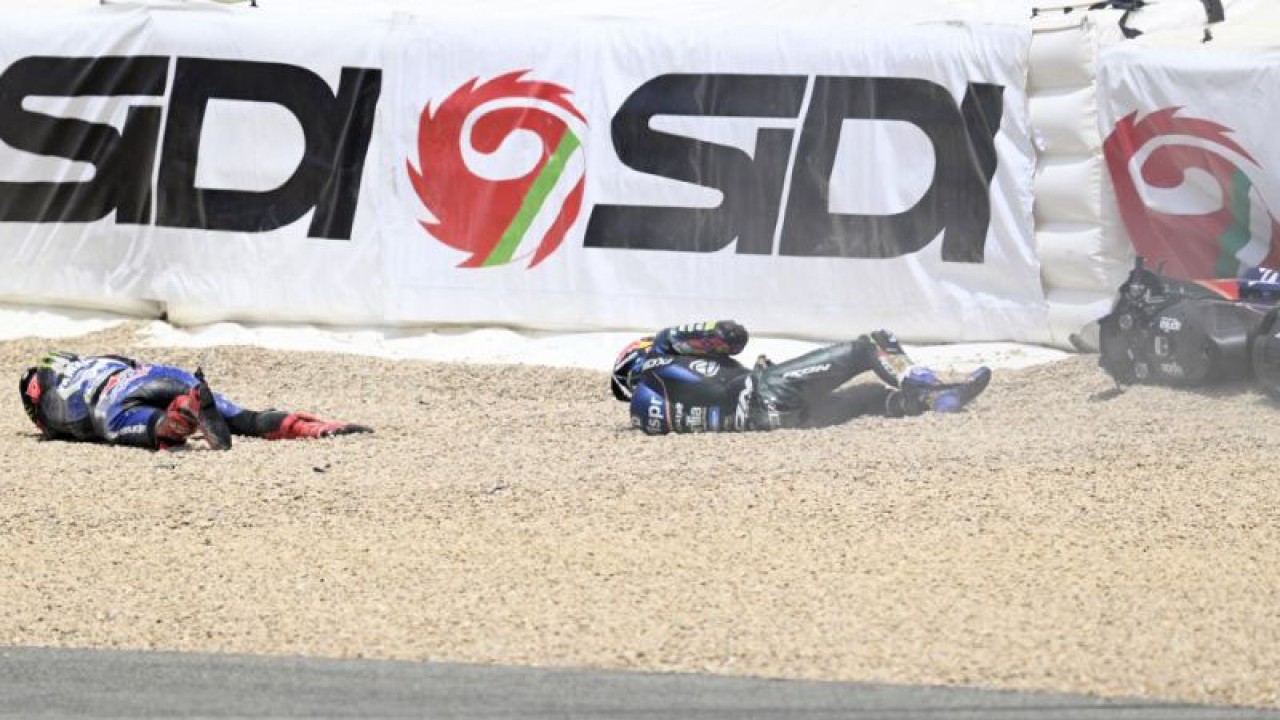 Pebalap Yamaha Fabio Quartararo (kiri) dan pebalap Aprilia Miguel Oliveira terbaring di tanah setelah terlibat kecelakaan di MotoGP Spanyol di Sirkuit Jerez, 30 April 2023. Foto AFP/JORGE GUERRERO