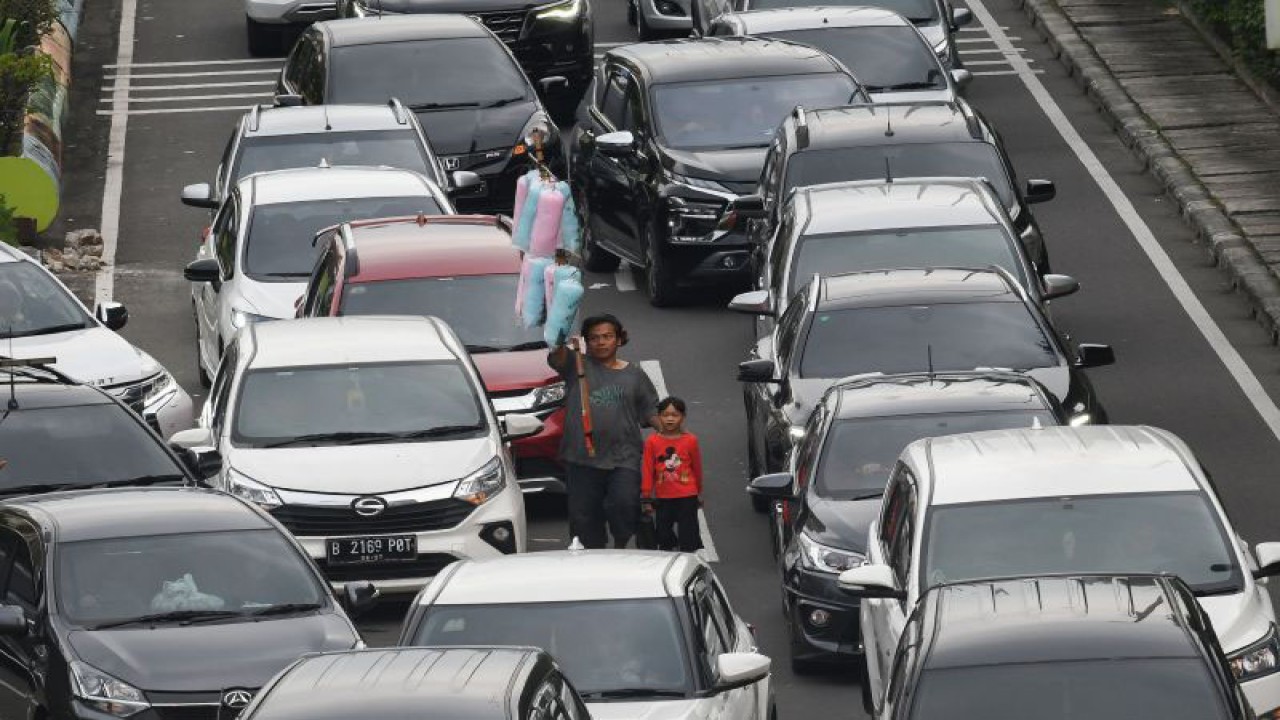 Pedagang asongan berjalan di antara kepadatan kendaraan bermotor di Jalan Benyamin Sueb ke arah arena Pekan Raya Jakarta (PRJ) JIExpo Kemayoran, Jakarta, Minggu (25/6/2023). Sejumlah pengguna jalan mengeluhkan kemacetan yang terjadi juga pada Sabtu (24/6) akibat penutupan jalan tersebut untuk ajang balapan Street Race. ANTARA FOTO/Aditya Pradana Putra/pras.