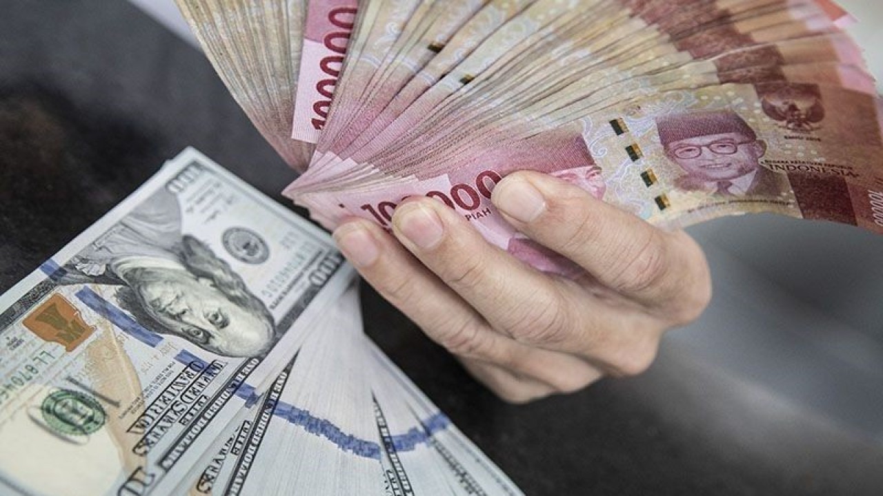 Ilustrasi - Petugas menunjukan uang pecahan rupiah dan dolar AS di gerai penukaran mata uang asing VIP (Valuta Inti Prima) Money Changer, Jakarta, Selasa (3/1/2023). ANTARA FOTO/Muhammad Adimaja/foc/pri.