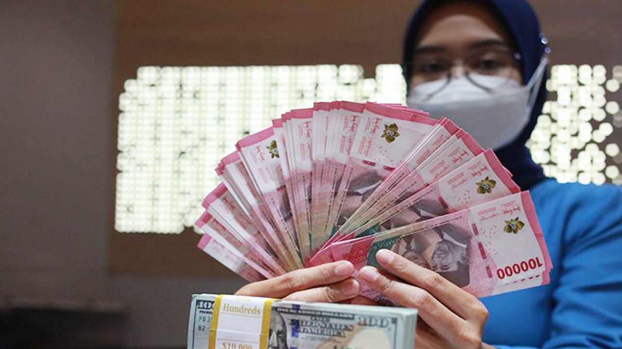 Ilustrasi - Petugas perbankan menunjukkan uang dolar AS dan uang rupiah. ANTARA FOTO/Reno Esnir/tom/aa. (ANTARA FOTO/RENO ESNIR)