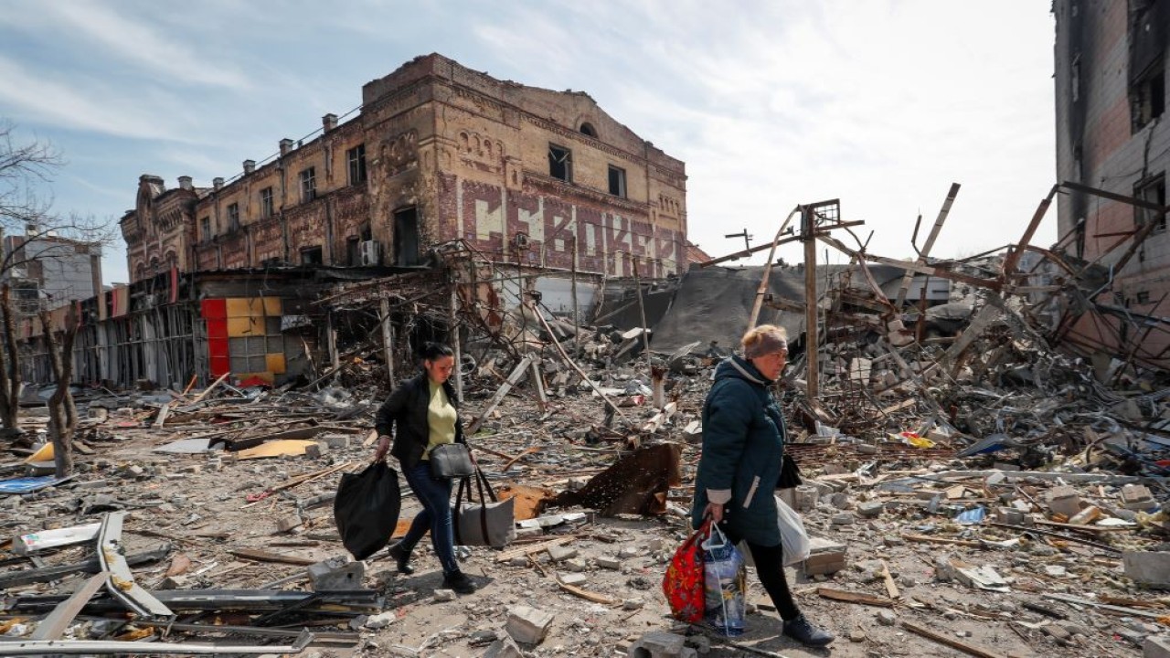 Warga membawa barang-barangnya di dekat bangunan yang hancur akibat konflik Ukraina-Rusia, di selatan kota pelabuhan Mariupol, Ukraina, 10 April 2022. (Alexander Ermochenko/Reuters)