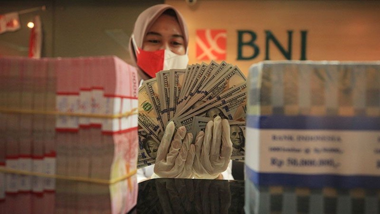 Petugas menghitung uang dolar AS dan uang rupiah di salah satu kantor cabang PT Bank Negara Indonesia (Persero) Tbk, KCU Melawai, Jakarta, Selasa (16/8/2022). ANTARA FOTO/Reno Esnir/foc.