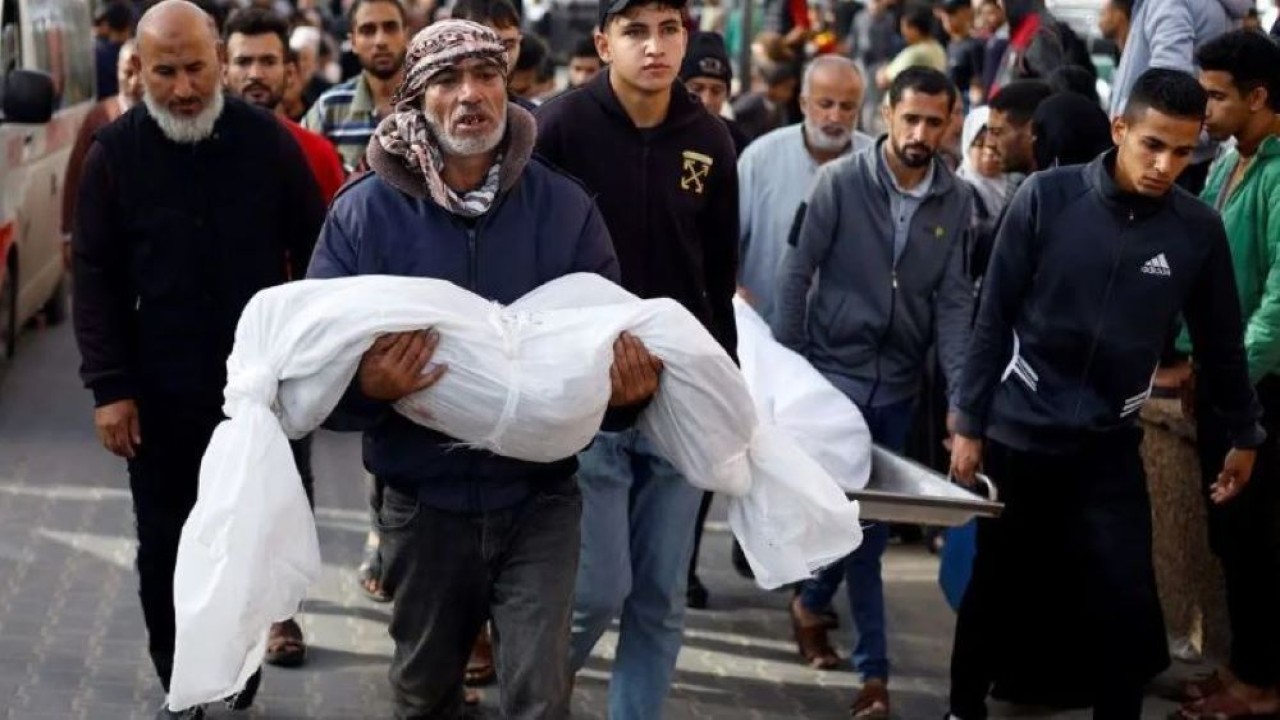 Seorang pria membawa jenazah seorang anak Palestina yang tewas dalam serangan Israel, di tengah konflik yang sedang berlangsung antara Israel dan kelompok Palestina Hamas, di Khan Younis di selatan Jalur Gaza, 19 November 2023. (Reuters)