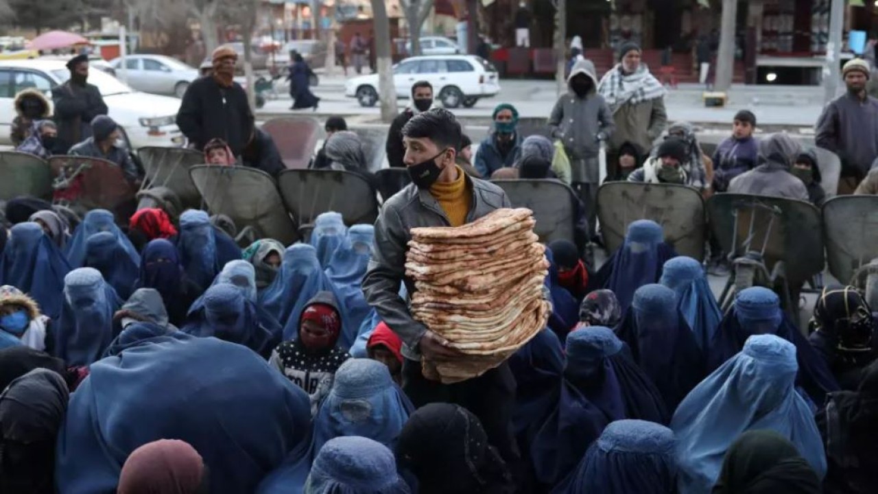 Seorang pria mendistribusikan roti di sebuah pasar di Kabul, Afghanistan, pada 31 Januari 2022. Kekeringan dan kehancuran perekonomian mendorong meningkatnya kelaparan. (Ali Khara/Reuters)