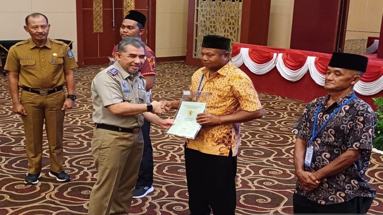 Kepala Kanwil BPN Kepri, Nurhadi Putra menyerahkan sertifikat tanah gratis kepada 200 warga Pulau Bintan di Aula Wan Seri Beni, Pulau Dompak, Tanjungpinang, Senin (4/12/2023). (ANTARA/Ogen)