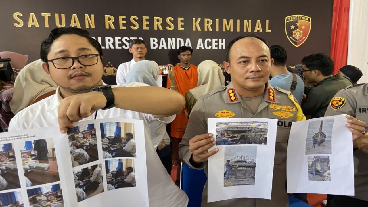 Kapolresta Banda Aceh Kombes Pol Fahmi Irwan Ramli (kanan) didampingi Kasat Reskrim Polresta Banda Aceh Kompol Fadhillah Aditya Pratama memperlihatkan barang bukti foto penyerahan uang dan kapal yang mengangkut pengungsi Rohingya saat rilis kasus penyuludupan manusia di Banda Aceh, Aceh, Senin (18/12/2023). (ANTARA/Khalis)