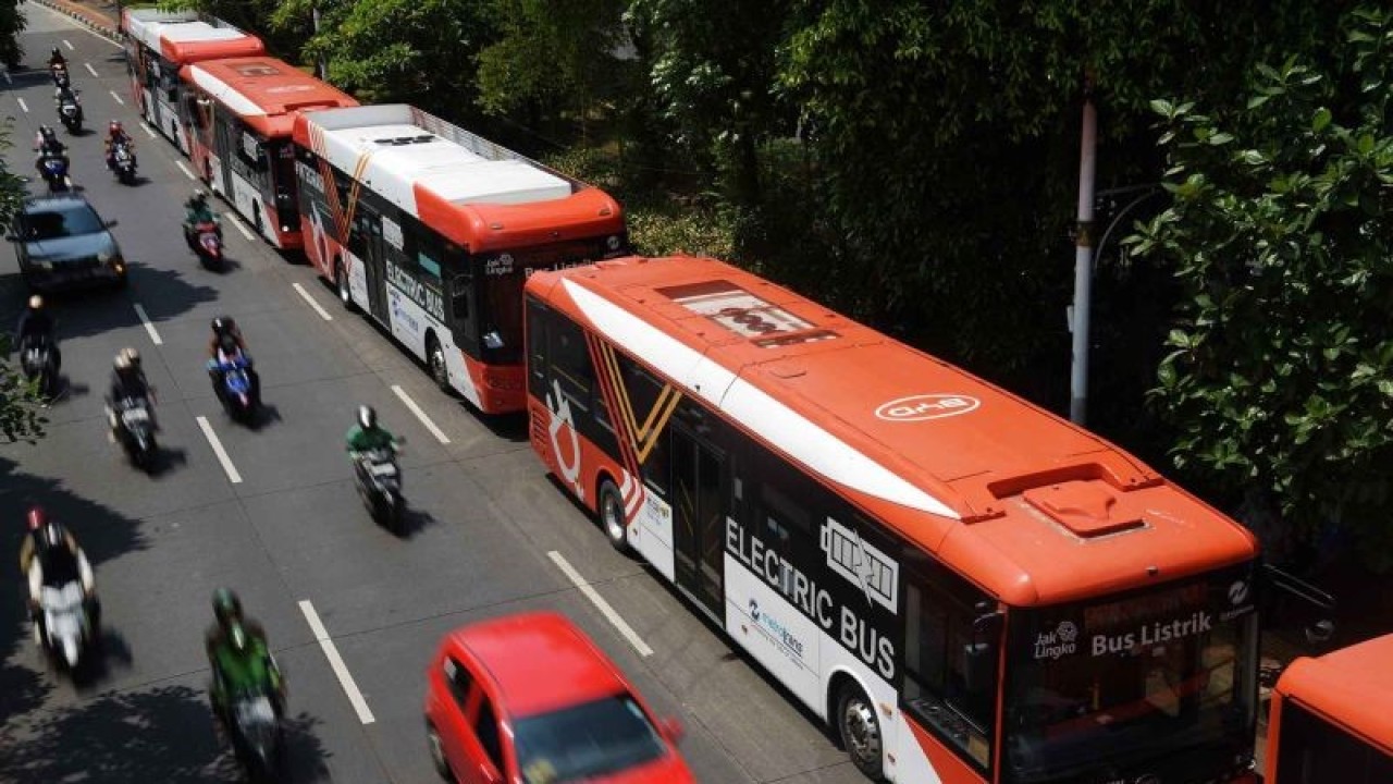 Sejumlah pengendara melaju di samping bus listrik Transjakarta di halte bus Universitas Indonesia, Depok, Jawa Barat, Minggu (31/12/2023). Penggunaan bus berbasis listrik itu menjadi salah satu langkah nyata untuk mencapai net zero emisi serta mewujudkan transportasi umum yang bertanggung jawab terhadap aspek lingkungan dan sosial yang berkelanjutan. ANTARA FOTO/Andika Wahyu/YU