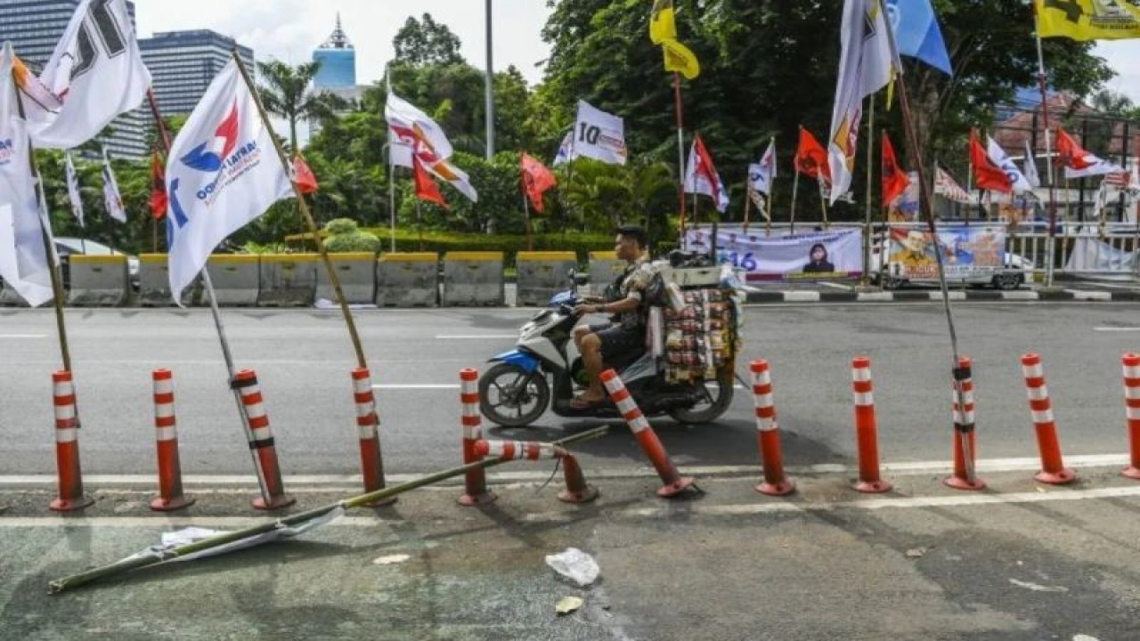 Pengendara melintas di samping alat peraga kampanye (APK) pemilu 2024 yang terpasang di pembatas jalur sepeda (stick cone) di kawasan Menteng, Jakarta, Senin (8/1/2024). ANTARA FOTO/Galih Pradipta/YU.