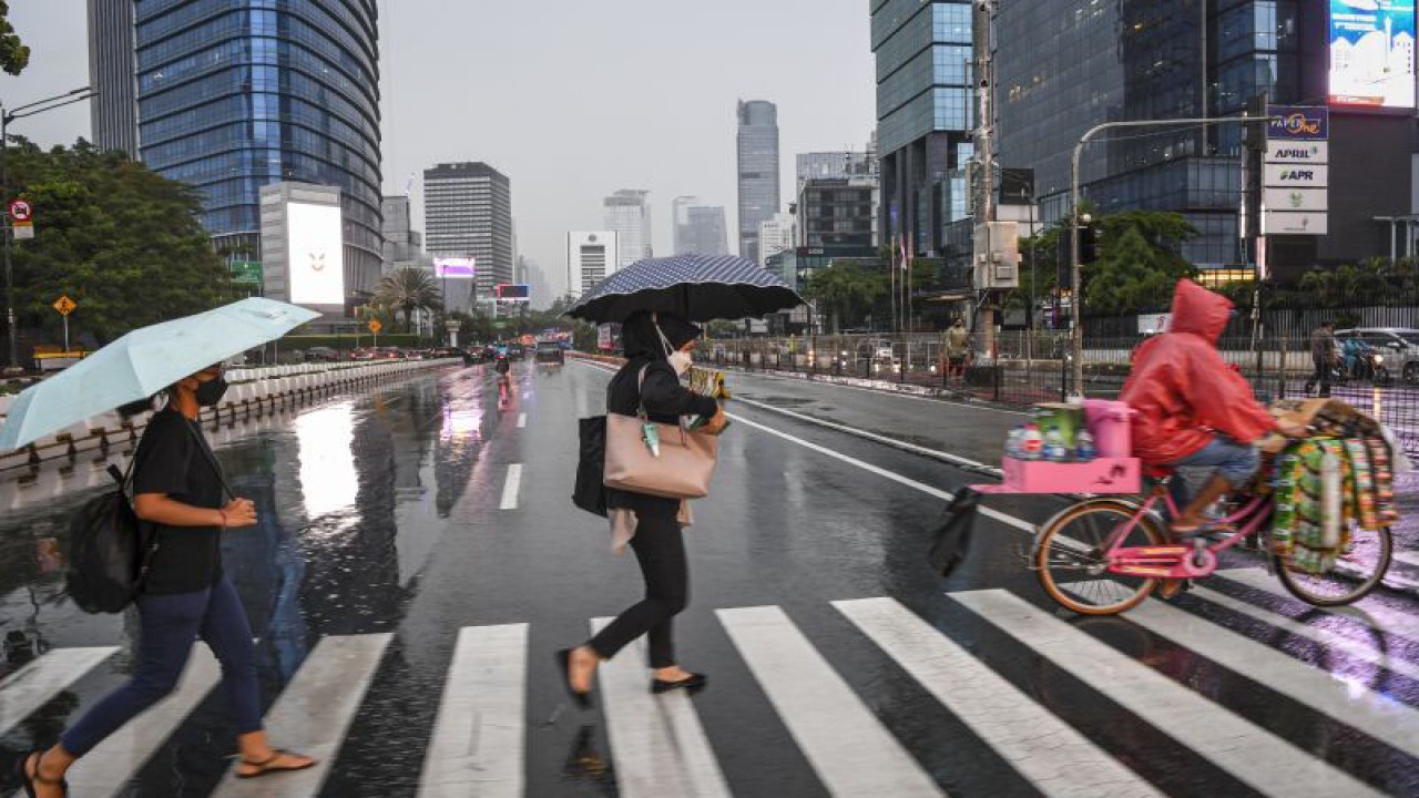 Sejumlah warga menggunakan payung saat hujan di kawasan Jalan Jenderal Sudirman, Jakarta, Selasa (4/10/2022). Badan Meteorologi Klimatologi dan Geofisika (BMKG) menyatakan potensi curah hujan dengan intensitas sedang hingga lebat yang dapat disertai kilat atau petir dan angin kencang untuk periode tanggal 2-8 Oktober 2022 di wilayah DKI Jakarta dengan status waspada. ANTARA FOTO/M Risyal Hidayat/tom. (ANTARA FOTO/M RISYAL HIDAYAT)
