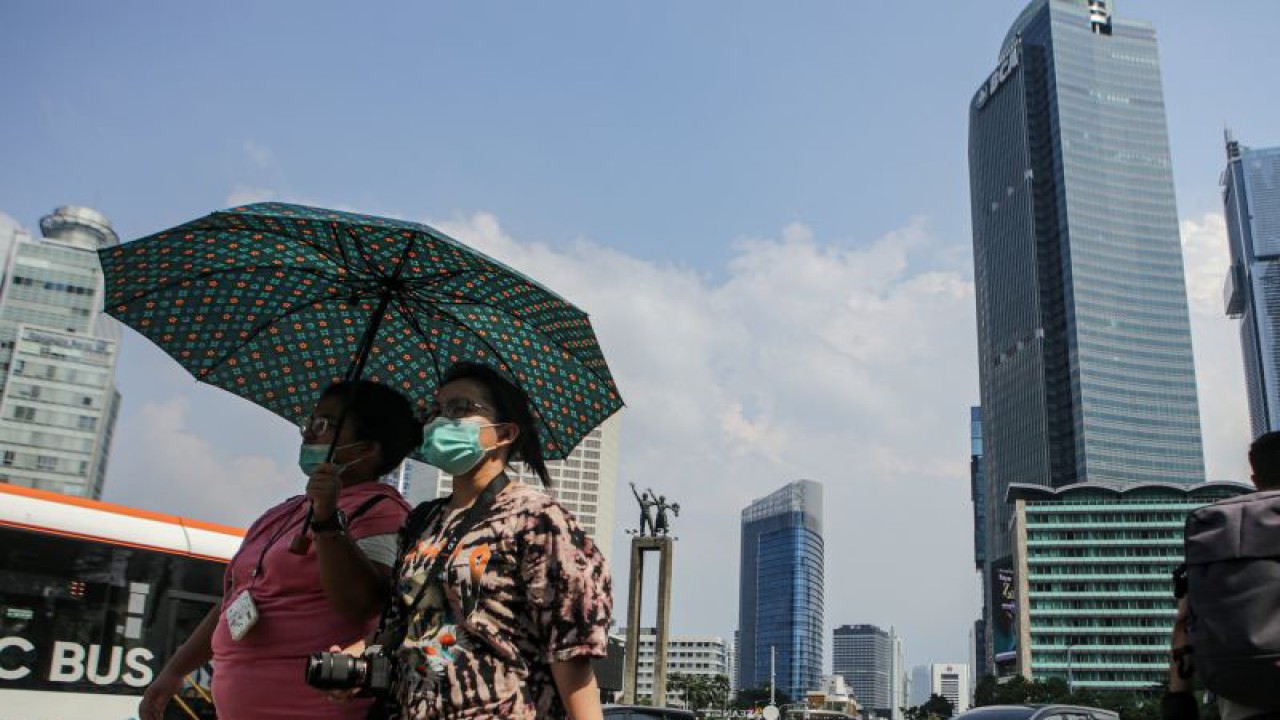 Warga berpayungan saat cuaca panas terik meliputi Jakarta pada Senin (24/4/2023). (ANTARA FOTO/Fauzan/aww)