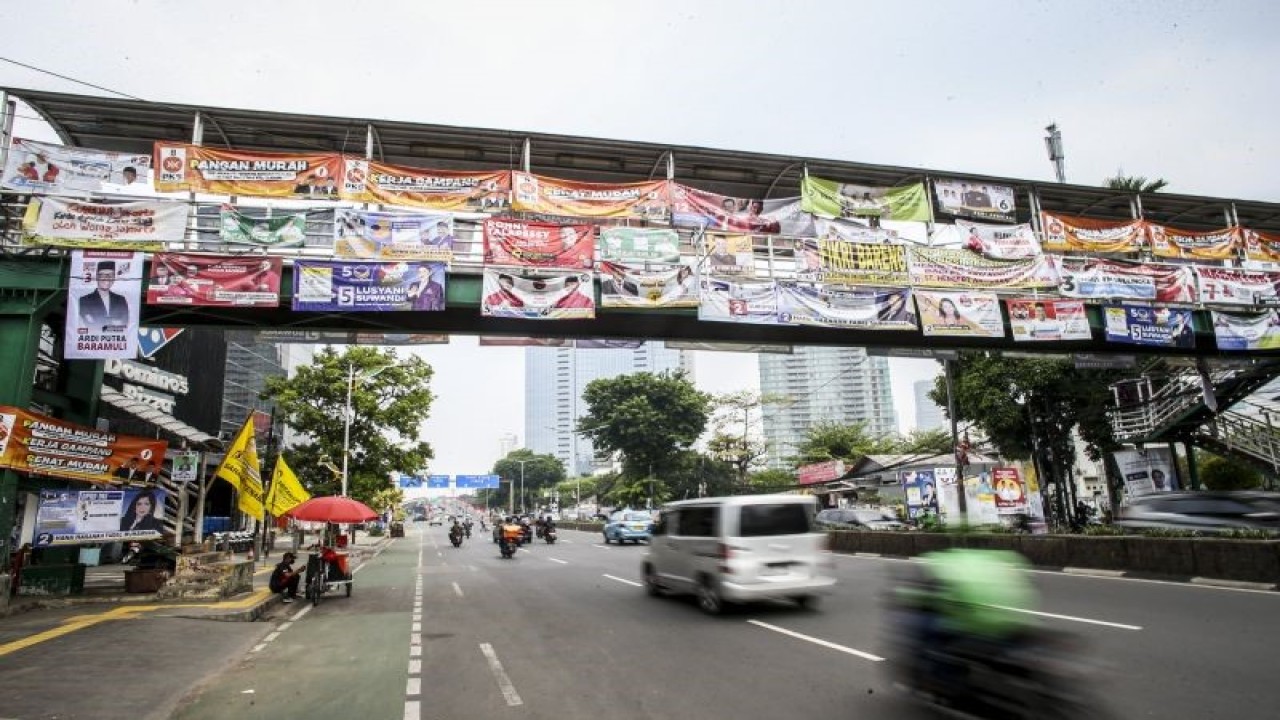 Kendaraan melintas di bawah Jembatan Penyeberangan Orang (JPO) yang tertutup oleh alat peraga kampanye Pemilu 2024 di Jakarta, Rabu (27/12/2023). ANTARA FOTO/Rivan Awal Lingga/tom.