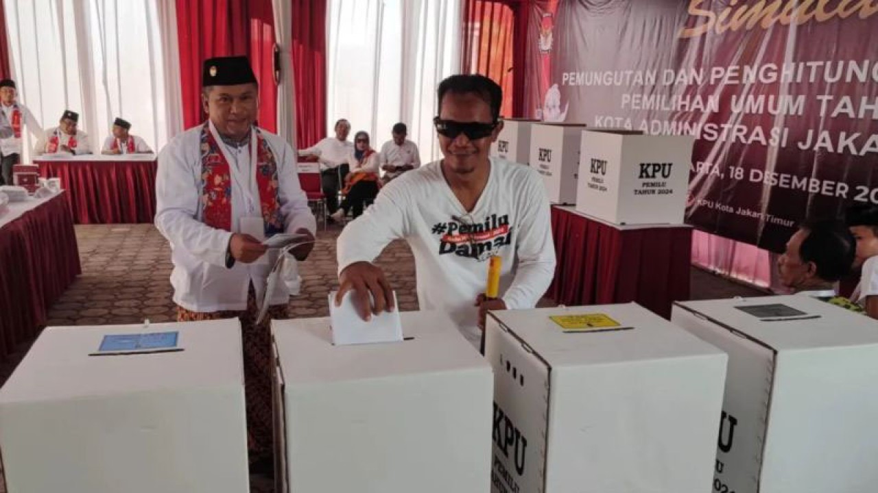 Petugas Kelompok Penyelenggara Pemungutan Suara (KPPS) mendampingi salah satu warga tuna netra saat memasukan surat suara ke kotak suara dalam simulasi pemungutan dan penghitungan suara Pemilu 2024 di Kantor KPU Jakarta Timur, Pulogadung, Senin (18/12/2023). ANTARA/Syaiful Hakim.