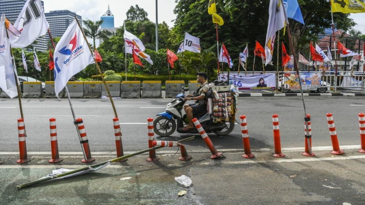 Pengendara melintas di samping alat peraga kampanye (APK) pemilu 2024 yang terpasang di pembatas jalur sepeda (stick cone) di kawasan Menteng, Jakarta, Senin (8/1/2024). .ANTARA FOTO/Galih Pradipta/YU