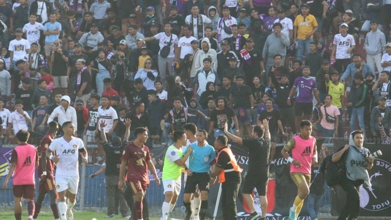 Petugas mengamankan wasit dari lemparan suporter saat pertandingan Persik Kediri melawan PSM Makassar pada kompetisi Liga 1 di Stadion Brawijaya, Kota Kediri, Jawa Timur, Senin (18/12/2023). Pertandingan tersebut dihentikan sementara selama 90 menit karena keputusan wasit mengesahkan gol PSM Makassar pada menit ke-86. ANTARA FOTO/Prasetia Fauzani/aww.