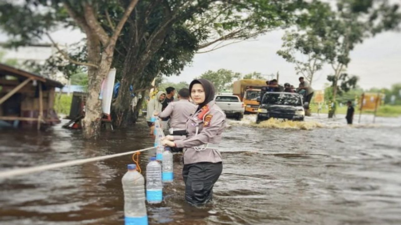 Kasatlantas Polres Rokan Hilir Iptu Zahratul Aulia Harun memasang penanda atau rambu-rambu di badan jalan terbuat dari botol bekas yang diberi scotlight di Jalan Lintas Riau-Sumatera Utara yang tergenang banjir. (ANTARA/HO-Polres Rokan Hilir)