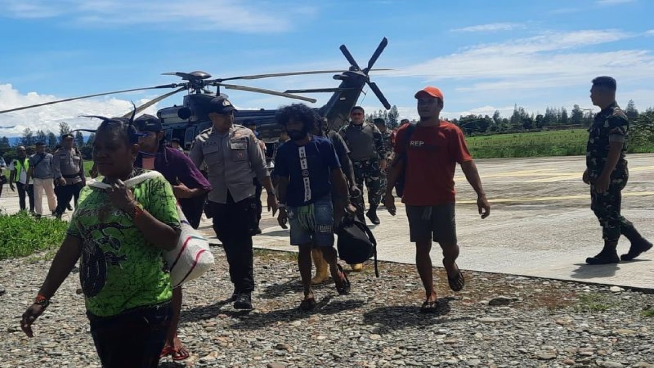 Anggota TNI-Polri yang tergabung dalam Satgas Operasi Damai Cartenz mengevakuasi sejumlah warga Kampung Alama Nduga, Nduga, Papua Pegunungan, dengan menggunakan helikopter saat tiba di Bandara Timika, Papua Tengah, Papua, Senin (20/02/2023). Sedikitnya 18 warga dievakuasi dan diungsikan ke Mimika imbas dari ancaman Kelompok Kriminal Bersenjata (KBB) pimpinan Egianus Kogoya di wilayah Nduga. ANTARA FOTO/HO-Humas Ops Damai Cartenz/tom. (ANTARA FOTO/Sakti Karuru)