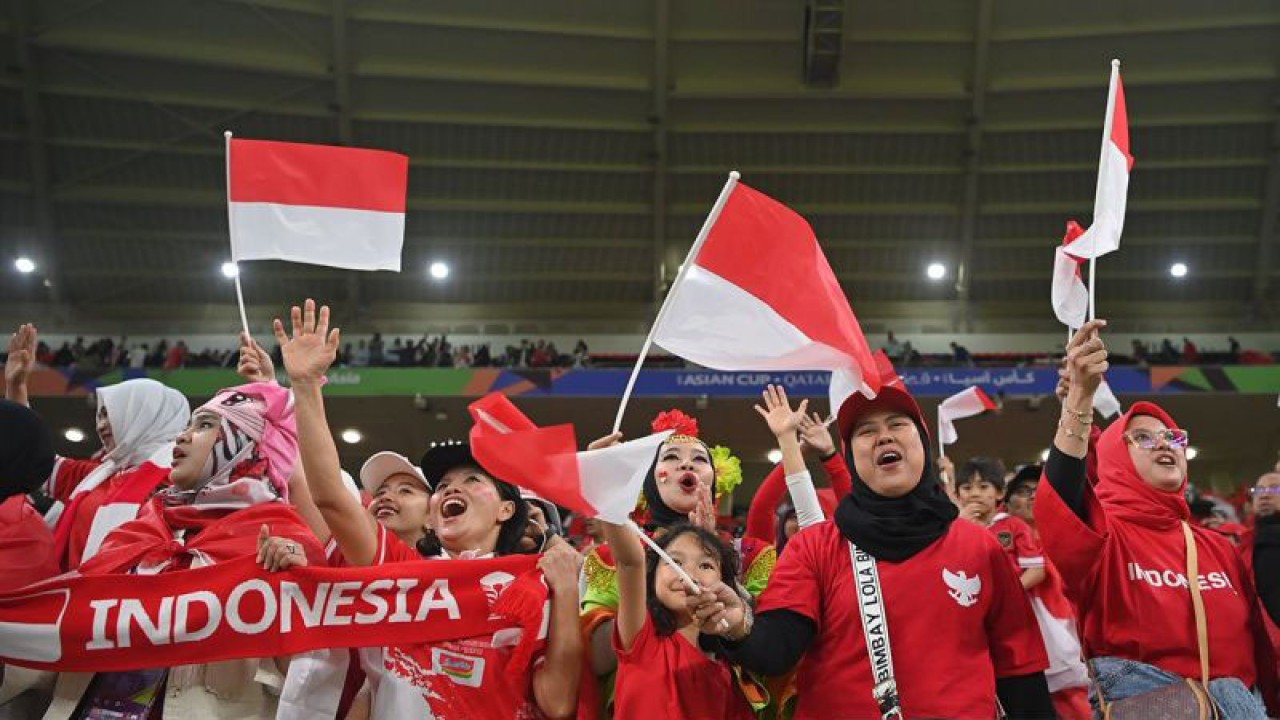 Arsip foto - Suporter Timnas Indonesia mengibarkan bendera merah putih seraya meneriakkan yel-yel dukungan saat laga Indonesia melawan Irak pada babak penyisihan grup D Piala Asia 2023 di Stadion Ahmad bin Ali Doha, Qatar, Senin (15/1/2024). ANTARA FOTO/Yusran Uccang/nz/pri.