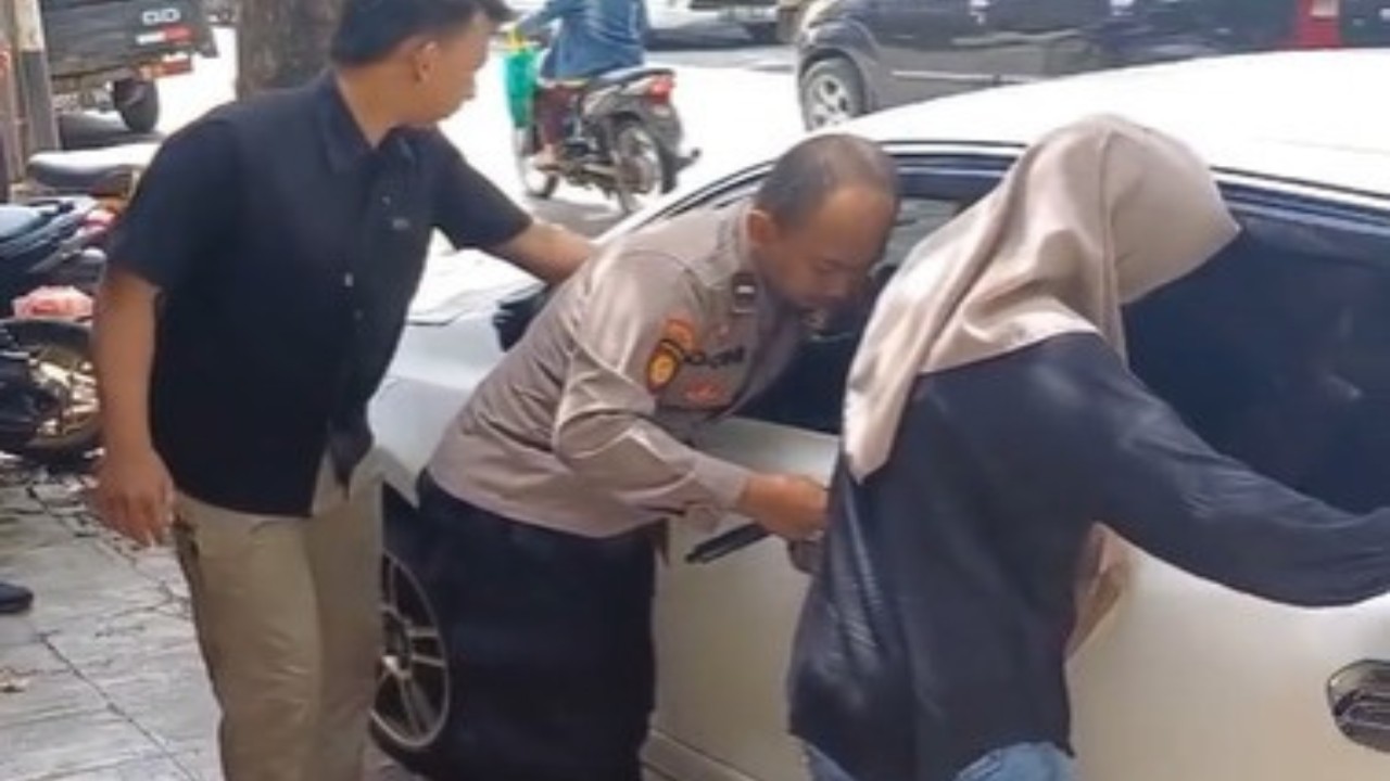 Seorang anggota kepolisian Aipda Donny Yanuar mengambil langkah cepat ketika seorang balita terkunci di dalam mobil. (Tangkap layar)