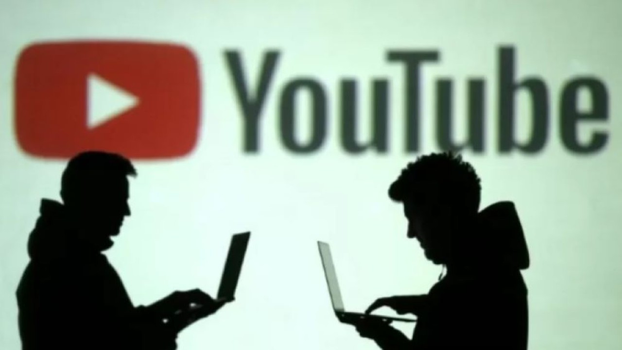 Ilustrasi. Siluet pengguna perangkat mobile terlihat di sebelah proyeksi layar logo YouTube. (Foto: Reuters)