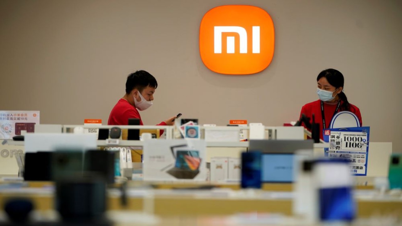 Anggota staf berdiri di dekat logo perusahaan di gerai Xiaomi di Shanghai, China, 1 November 2021. (Foto: REUTERS/Aly Song)