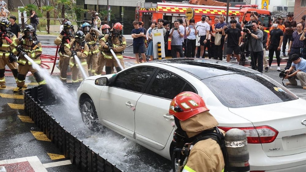 Petugas pemadam kebakaran memadamkan kebakaran kendaraan listrik selama latihan di kompleks apartemen di Busan, menyusul serangkaian insiden serupa baru-baru ini. (Foto: Yonhap)