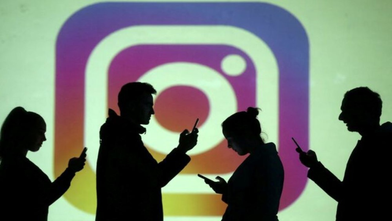 Ilustrasi. Siluet pengguna ponsel terlihat di samping proyeksi layar logo Instagram. (Foto: Dado Ruvic/Reuters)