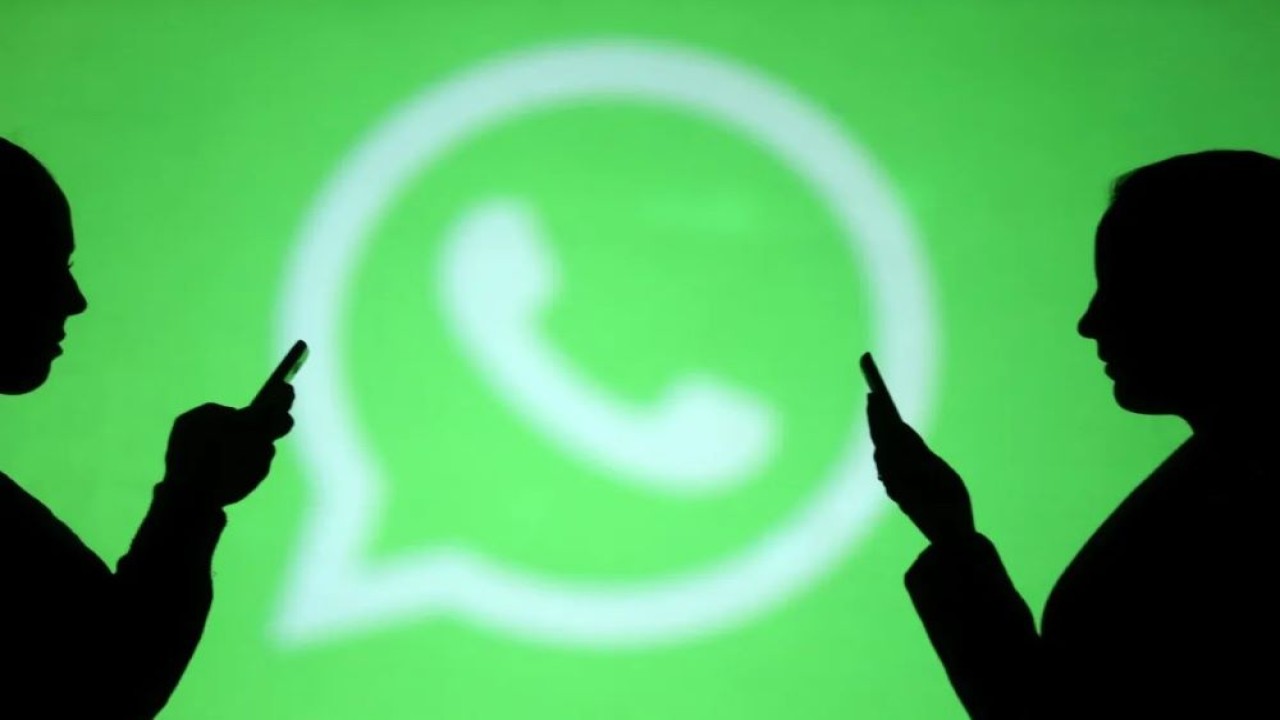 Siluet pengguna ponsel di samping layar logo WhatsApp. (Foto: Dado Ruvic/Reuters)