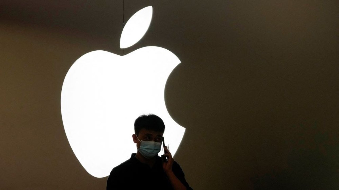 Seorang pria berbicara dengan ponsel di depan logo Apple di luar gerai Apple di Shanghai, China, 7 November 2022. (Foto: Dok/Aly Song/Reuters)