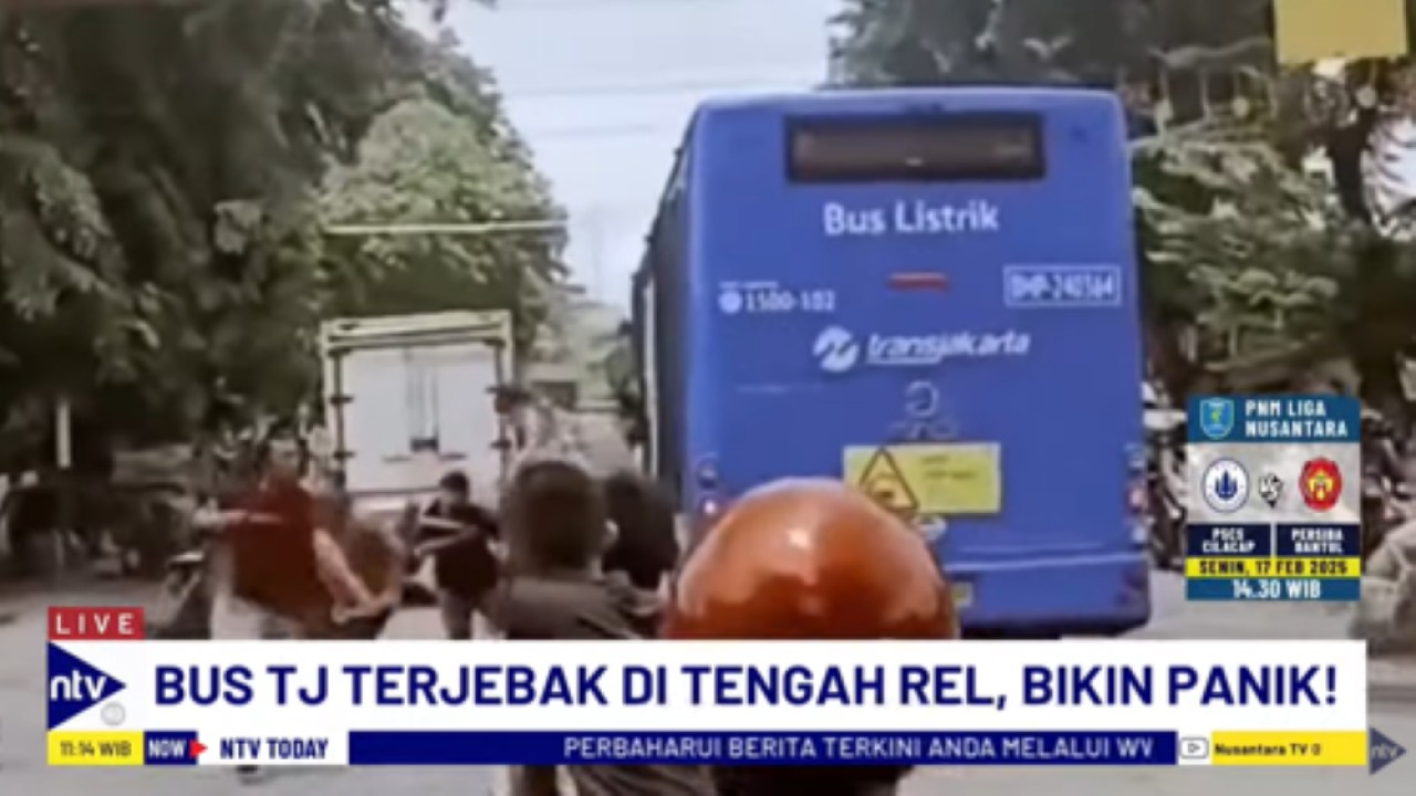 Penumpang berhamburan keluar dari bus Transjakara yang terjebak di tengah rel perlintasan KRL Green Garden Jakarta Barat