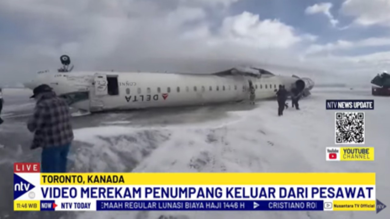 Petugas pemadam kebakaran menyiramkan air ke tubuh pesawat Delta Airlines yang terbalik dan mengeluarkan asap